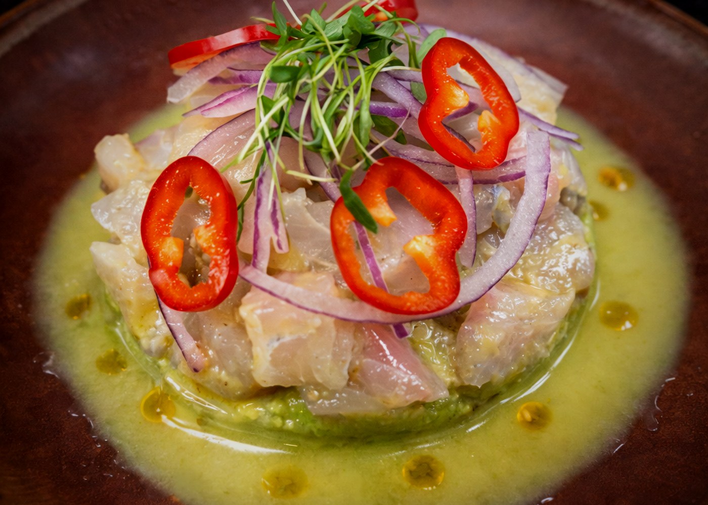 Fresh ceviche with citrus aguachile, red chili, and microgreens
