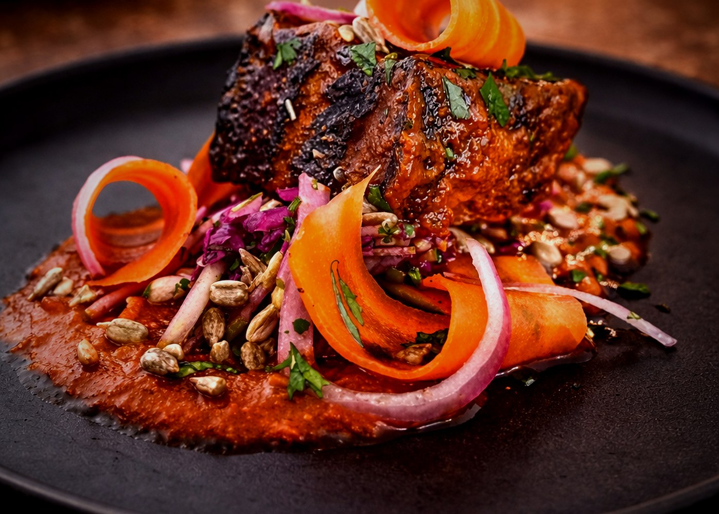 Pork belly with pasilla sauce, pickled onions, and pepitas — Casa Tequila Prime signature dish