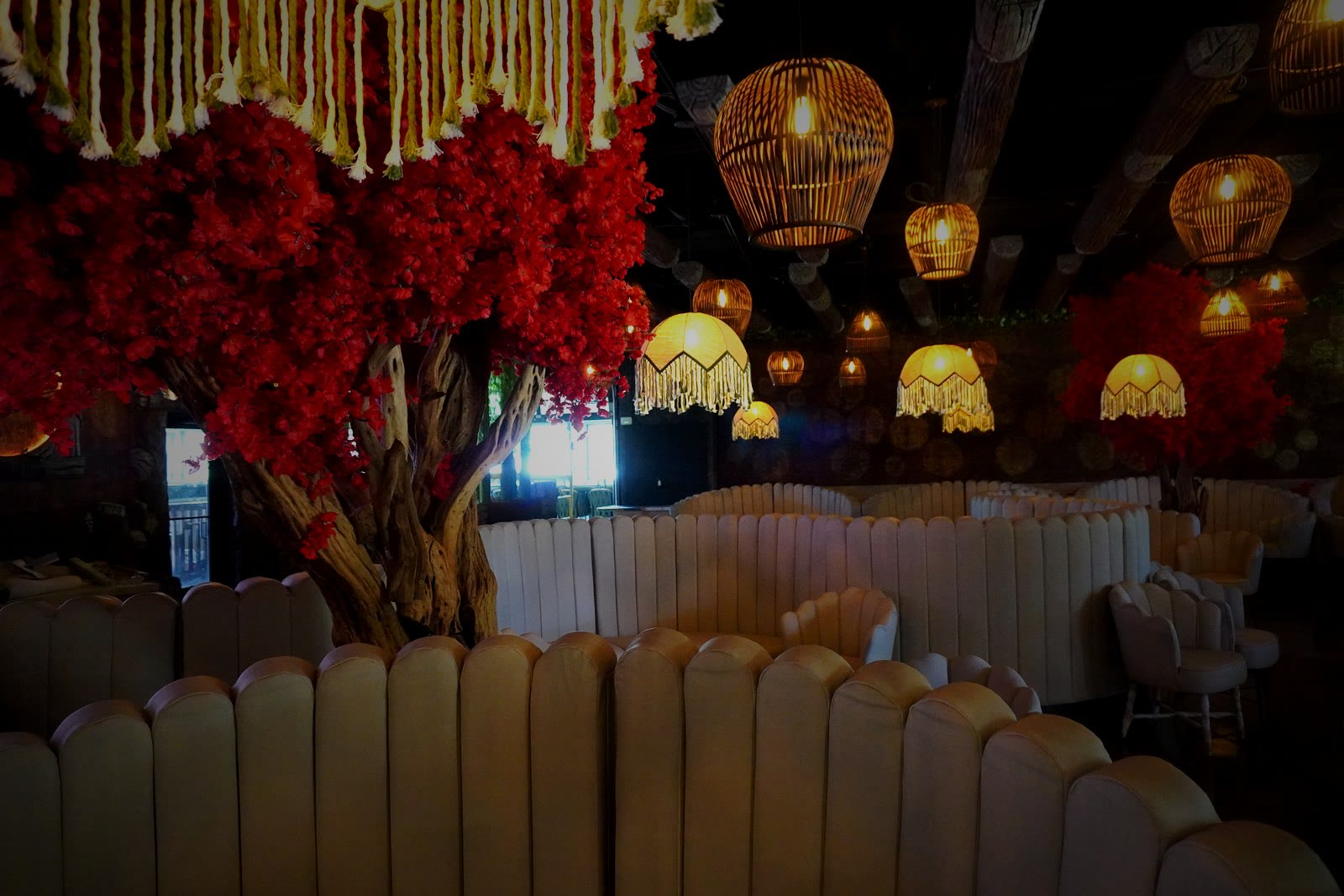Casa Tequila Prime main dining room — red flowering trees, amber pendant lights, and luxury booths