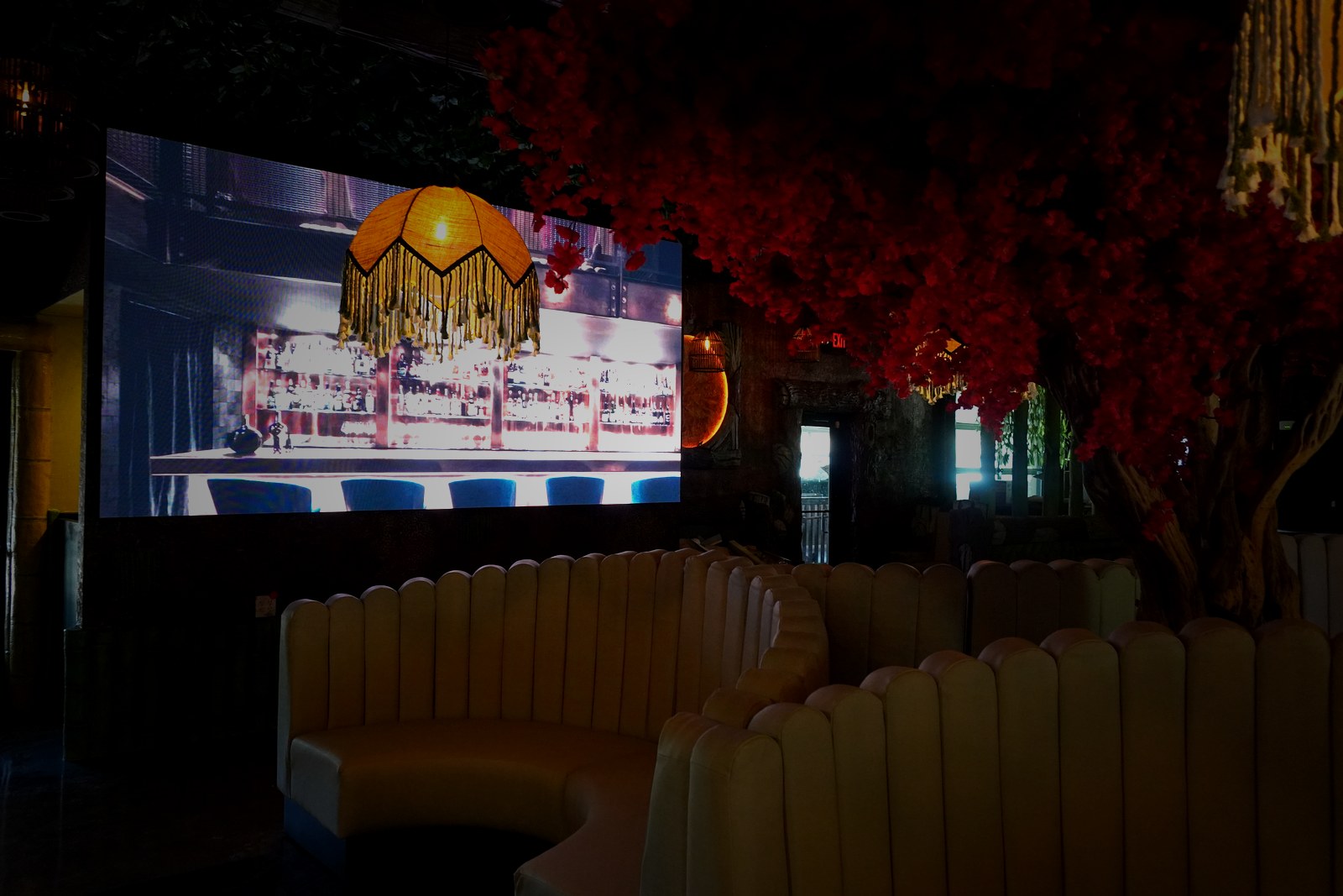 Casa Tequila Prime luxury interior — warm amber lighting, premium seating, and dramatic red flowering trees